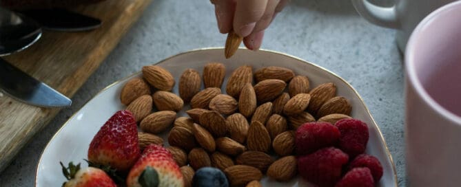 someone snacking on almonds, blueberries, raspberries and strawberries
