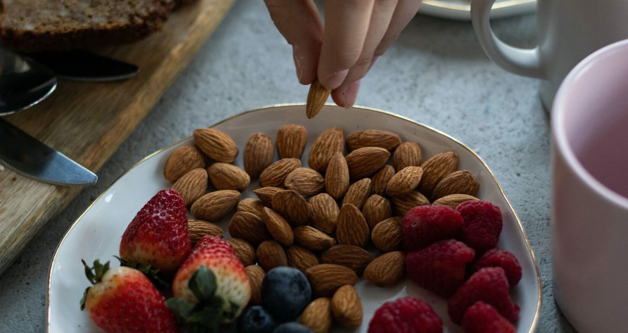 someone snacking on almonds, blueberries, raspberries and strawberries