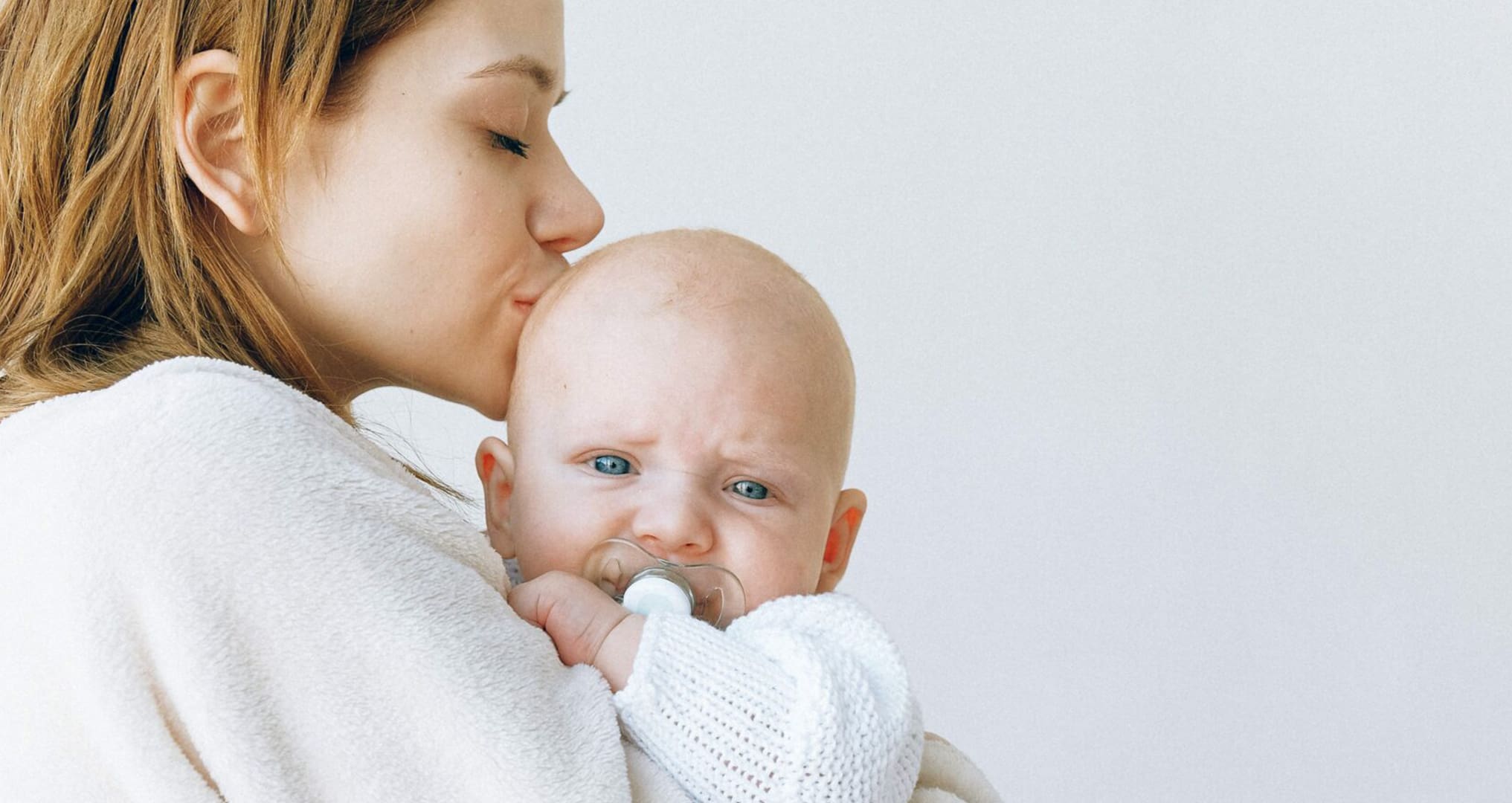 woman kissing child on forehead
