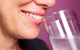 woman smiling and drinking a glass of water