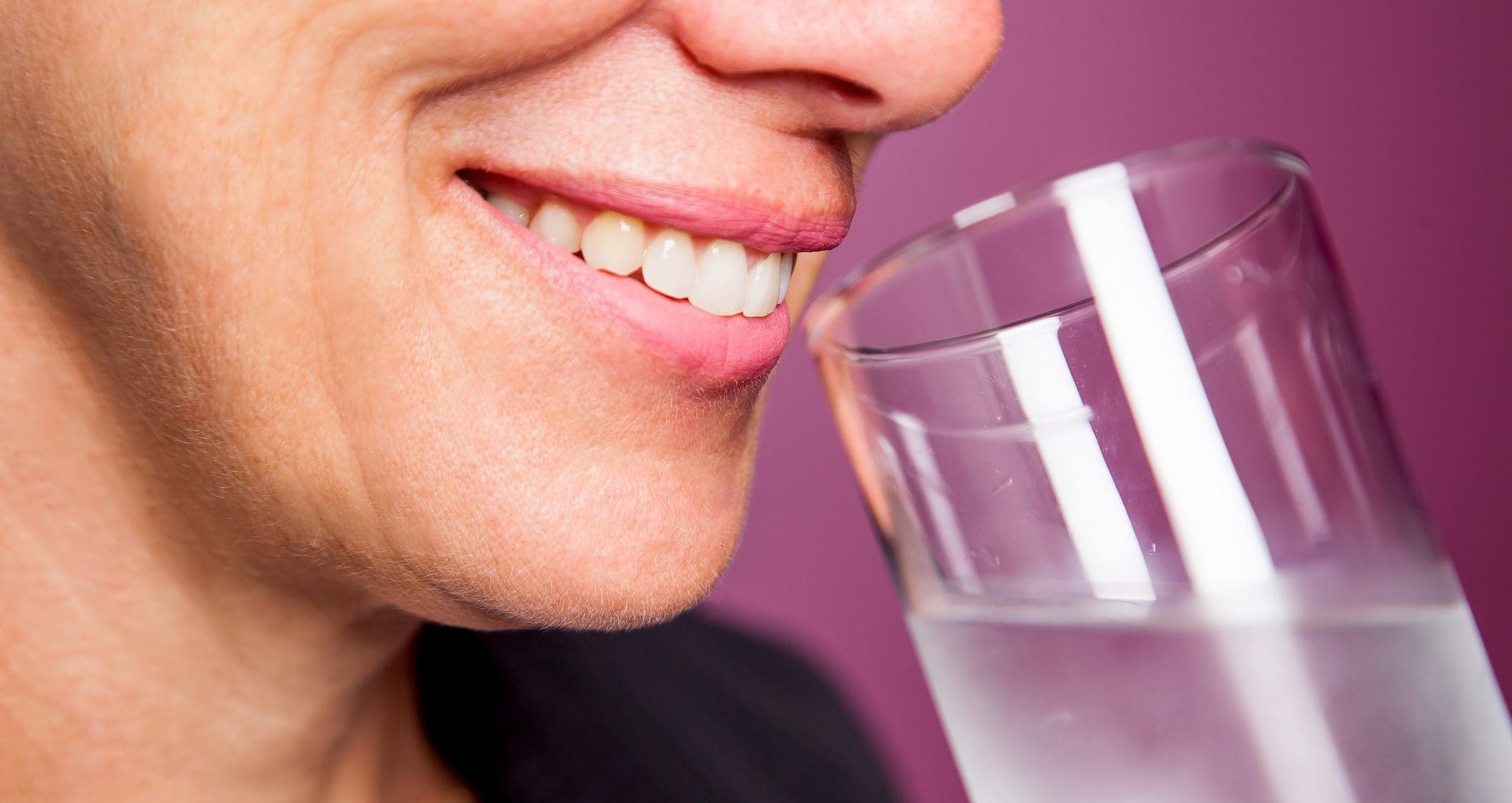woman smiling and drinking a glass of water