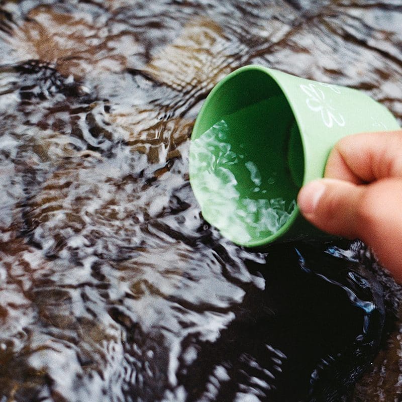 person getting a cup of water from river person getting a cup of water from river