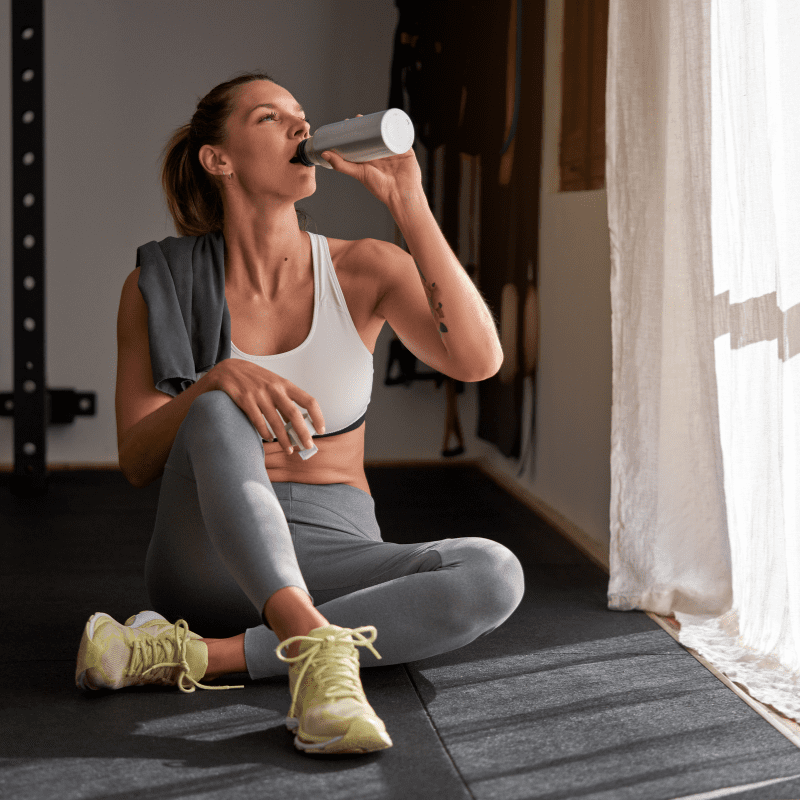 fit woman drinking water after exercising