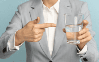 woman holding and pointing to a glass of water