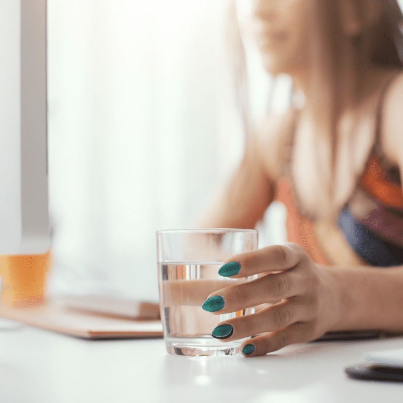 woman reaching for water glass while working woman reaching for water glass while working