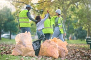 volunteer-child-and-people-high-five-while-cleani-2023-11-27-05-24-30-utc Volunteer, child and people high five while cleaning park with garbage bag for a clean environment