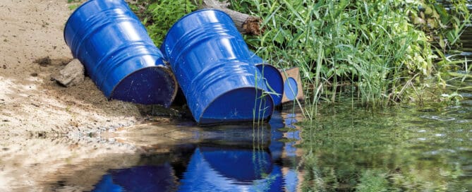 blue toxic chemical barrels sitting along the river’s edge.