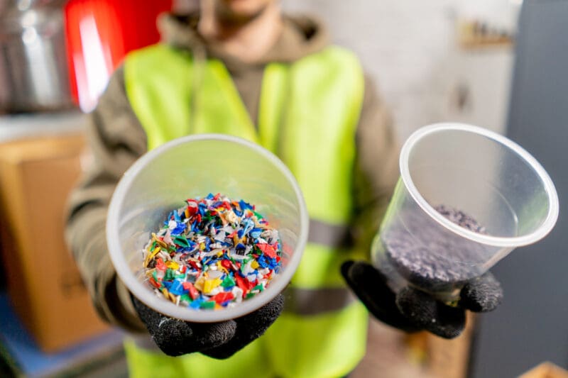 Close-up shot of shredded plastic bottle caps for further recycling at a waste recycling plant.