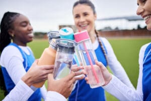 group of athletes cheering with their reusable water bottles