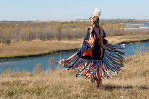 Women’s Fancy Shawl Dance Movement Native American tribal member dancing on bank of river.