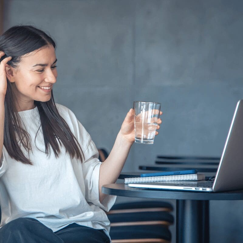young-woman-with-a-glass-of-water (1) young woman drinking from glass in front of her computer