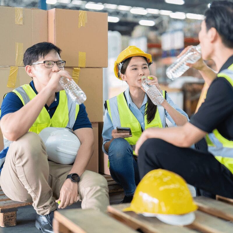 staff-in-large-storage-warehouse-drinking water together workers in warehouse drinking from plastic bottles