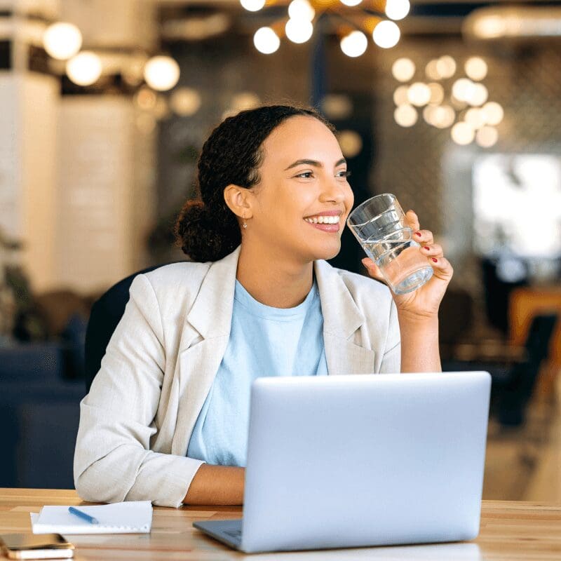 young woman drinking still water at her desk
