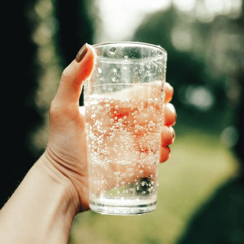 woman’s hand holding glass of sparkling water