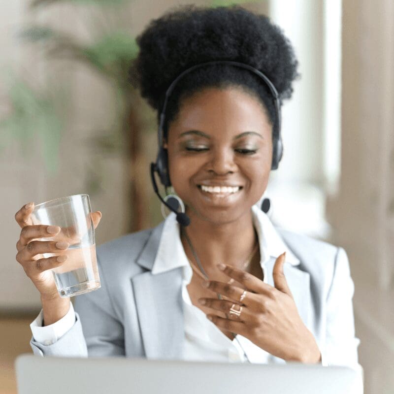 afro-woman-wear-headphones-work-at-laptop-at-office woman wearing headphones at work, holding a glass of water